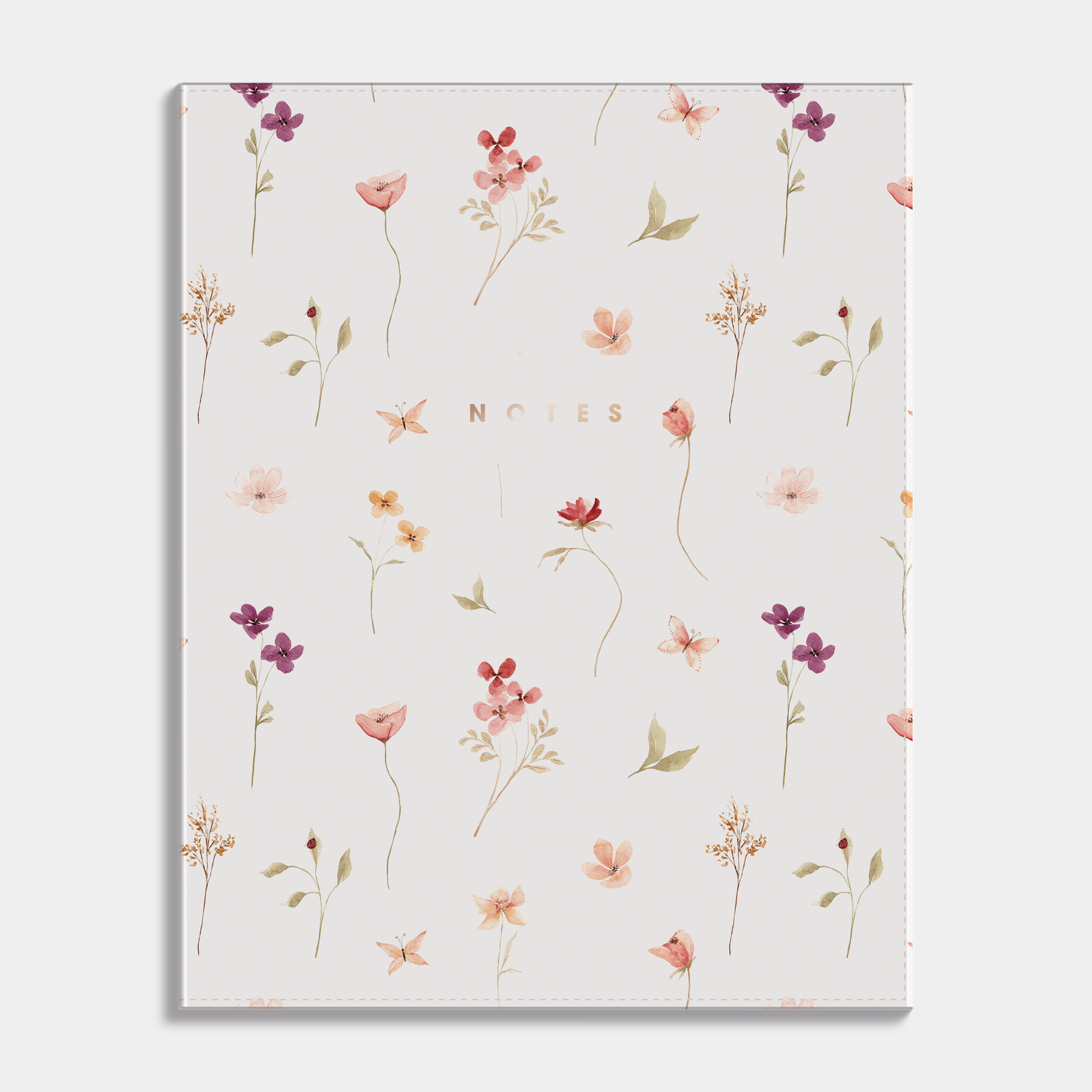 Notebook with a flexible cover and a design of delicate flowers on a light background. Frontal view.